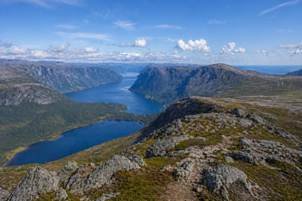 This image shows two kayakers paddling across the calm waters near Norris Point, Newfoundland, surrounded by towering cliffs, forested hillsides, and the scenic beauty of Bonne Bay. Kayaking in Norris Point is a popular outdoor activity that lets visitors explore the coastline, watch for wildlife, and experience Gros Morne National Park from the water.